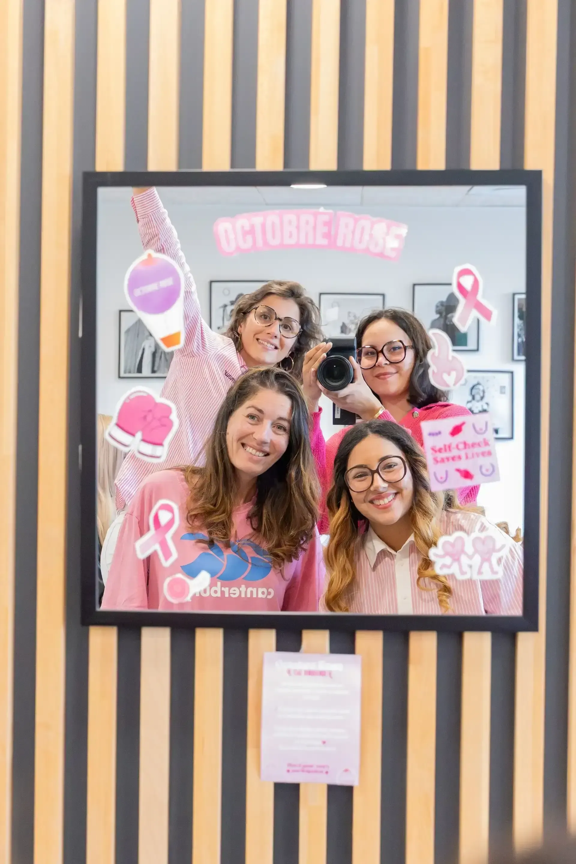 Équipe de l’ESD mobilisée pour Octobre Rose devant un miroir décoré de rubans roses